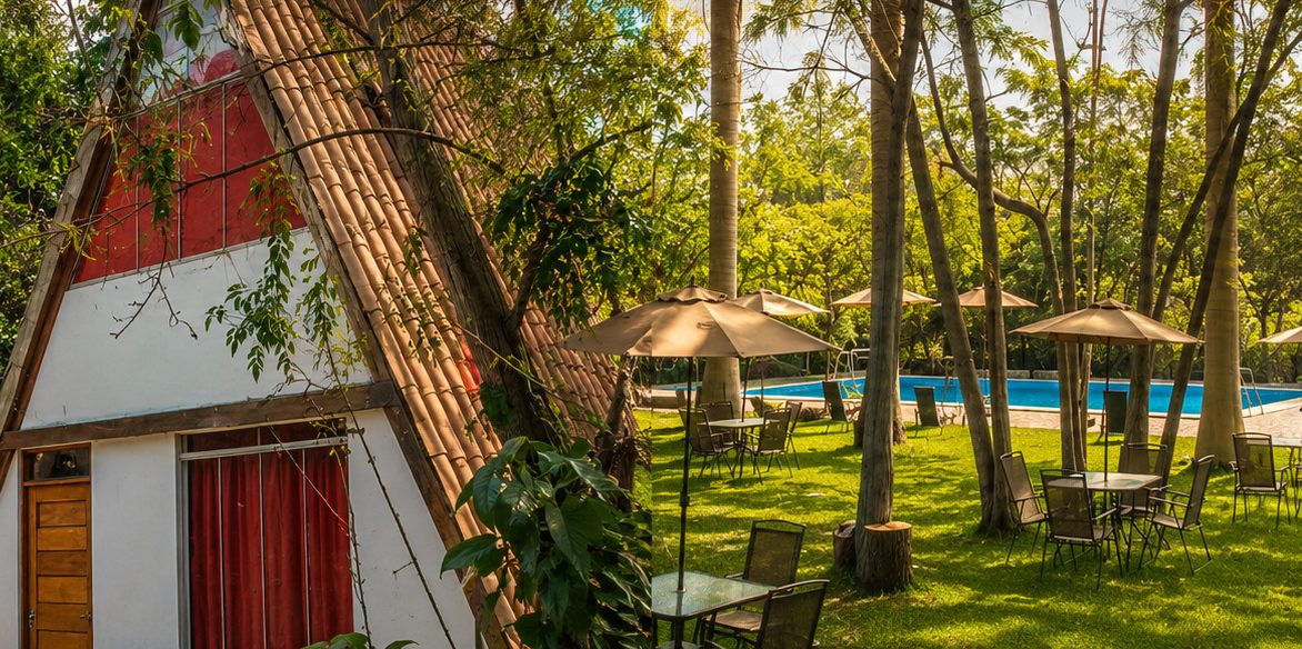 Cabañas triangulares junto a la piscina con las montañas de fondo en Alpina Eco Lodge